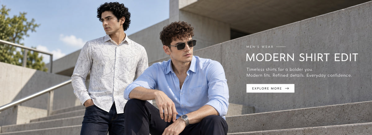 Two men modeling shirts on outdoor concrete steps under a blue sky. One man wears a white patterned long-sleeve shirt and dark pants, while the other wears a light blue patterned long-sleeve shirt and dark pants, both wearing sunglasses.