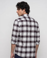 A man wearing a white long-sleeve plaid button-down shirt with dark brown and black checkered lines, shown from a three-quarter back view against a light gray background.