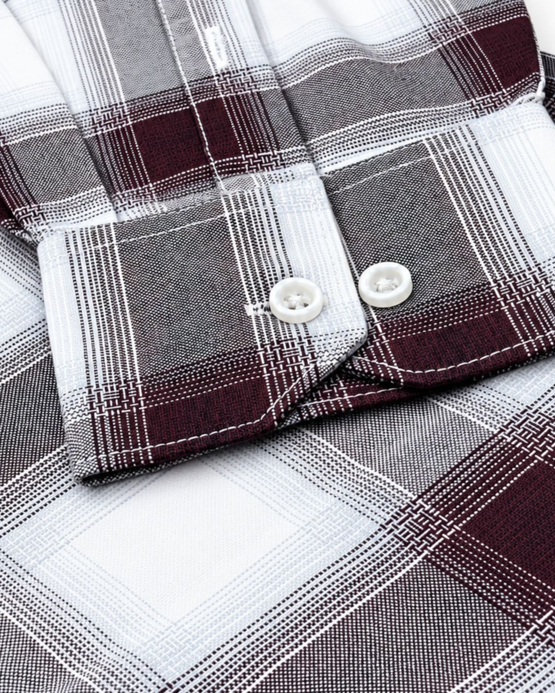 Close-up of a plaid button-up shirt showing the folded cuff with white buttons, featuring a pattern of white, gray, and dark burgundy plaid.