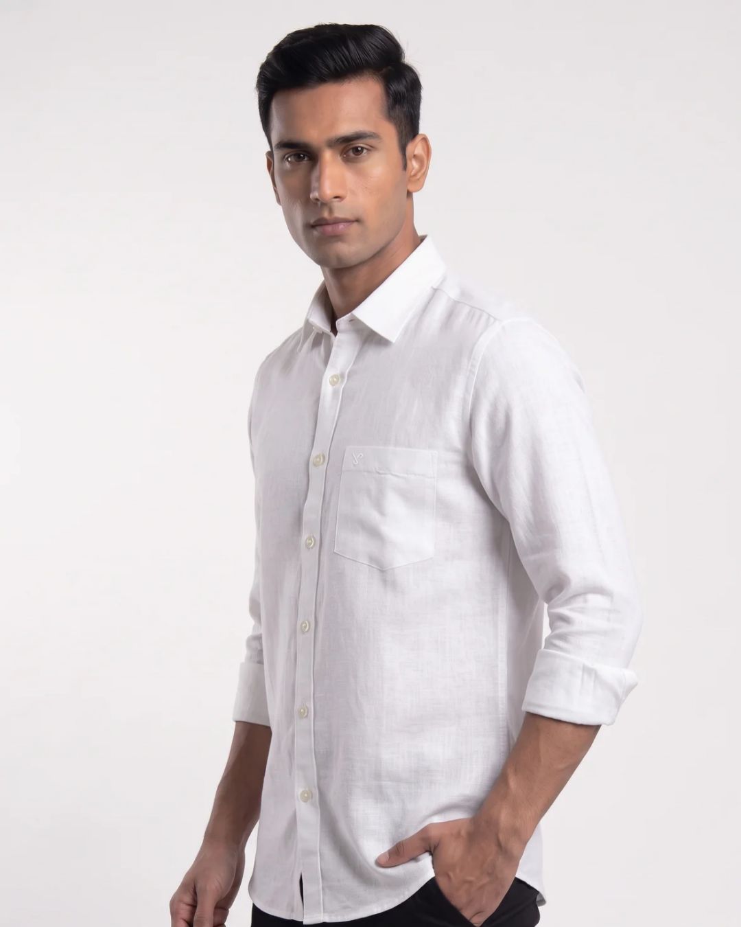 A man wearing a white long-sleeve linen shirt with a chest pocket, shown from the waist up against a plain light gray studio background.
