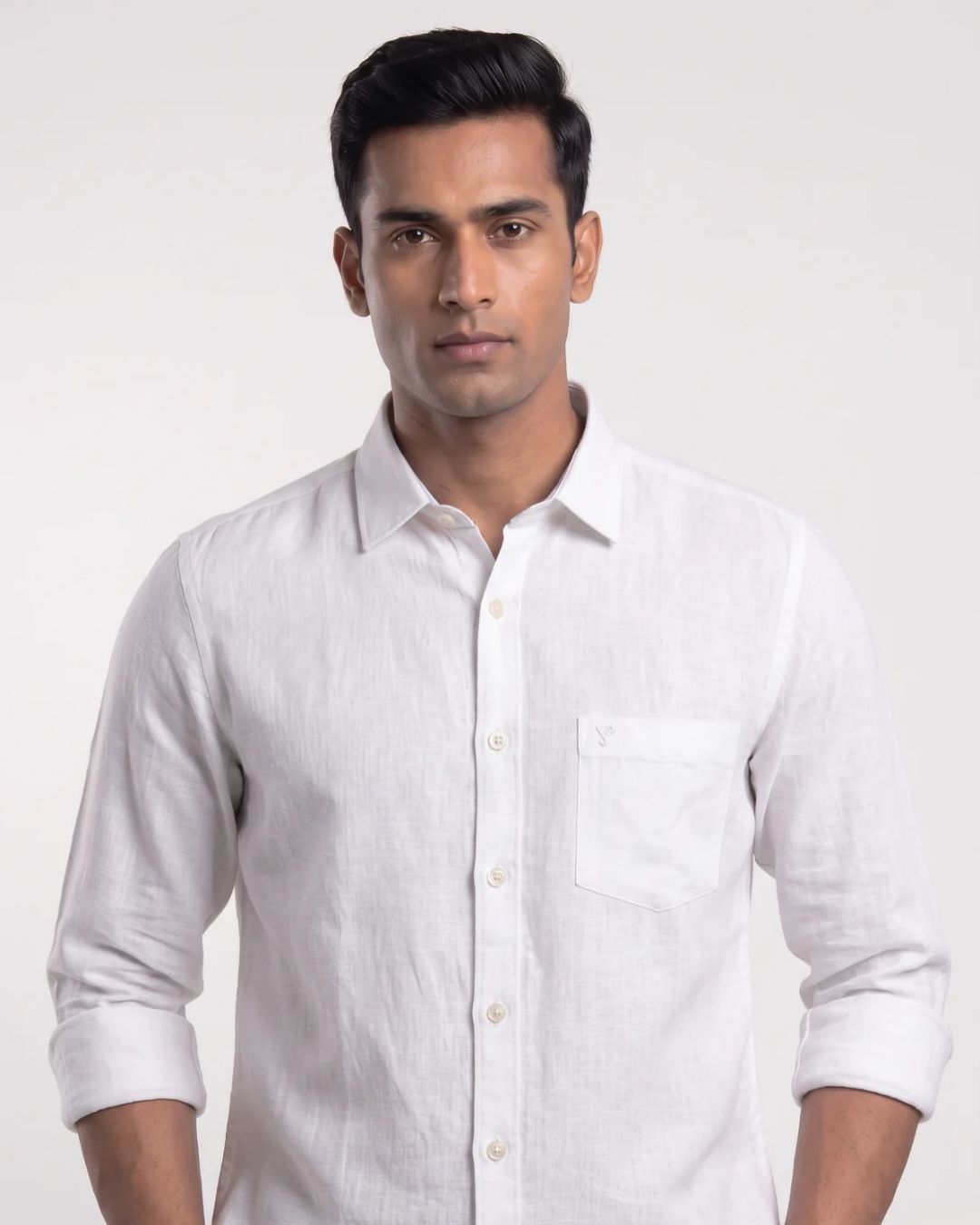 A man wearing a white long-sleeve linen shirt with a chest pocket, shown from the waist up against a light gray studio background.