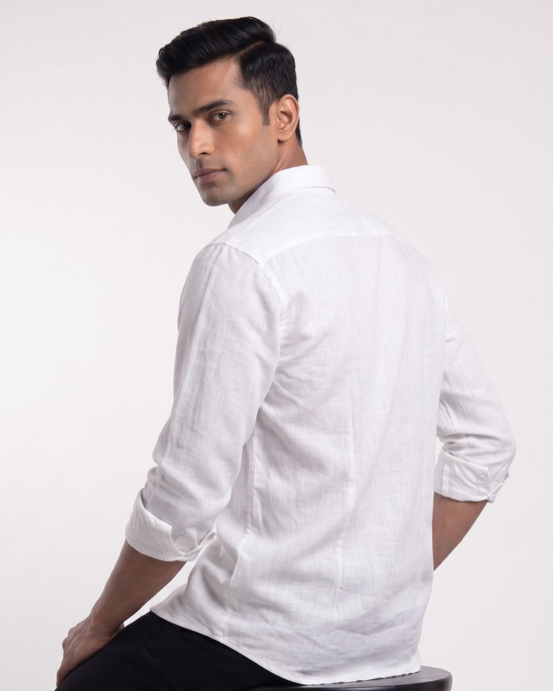 A man wearing a white long-sleeve linen shirt, shown from a three-quarters back view against a plain white studio background.