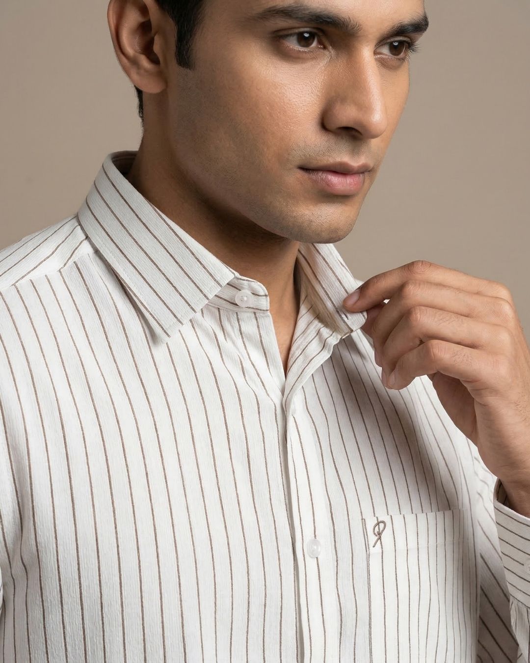 Man wearing a white striped shirt against a beige background