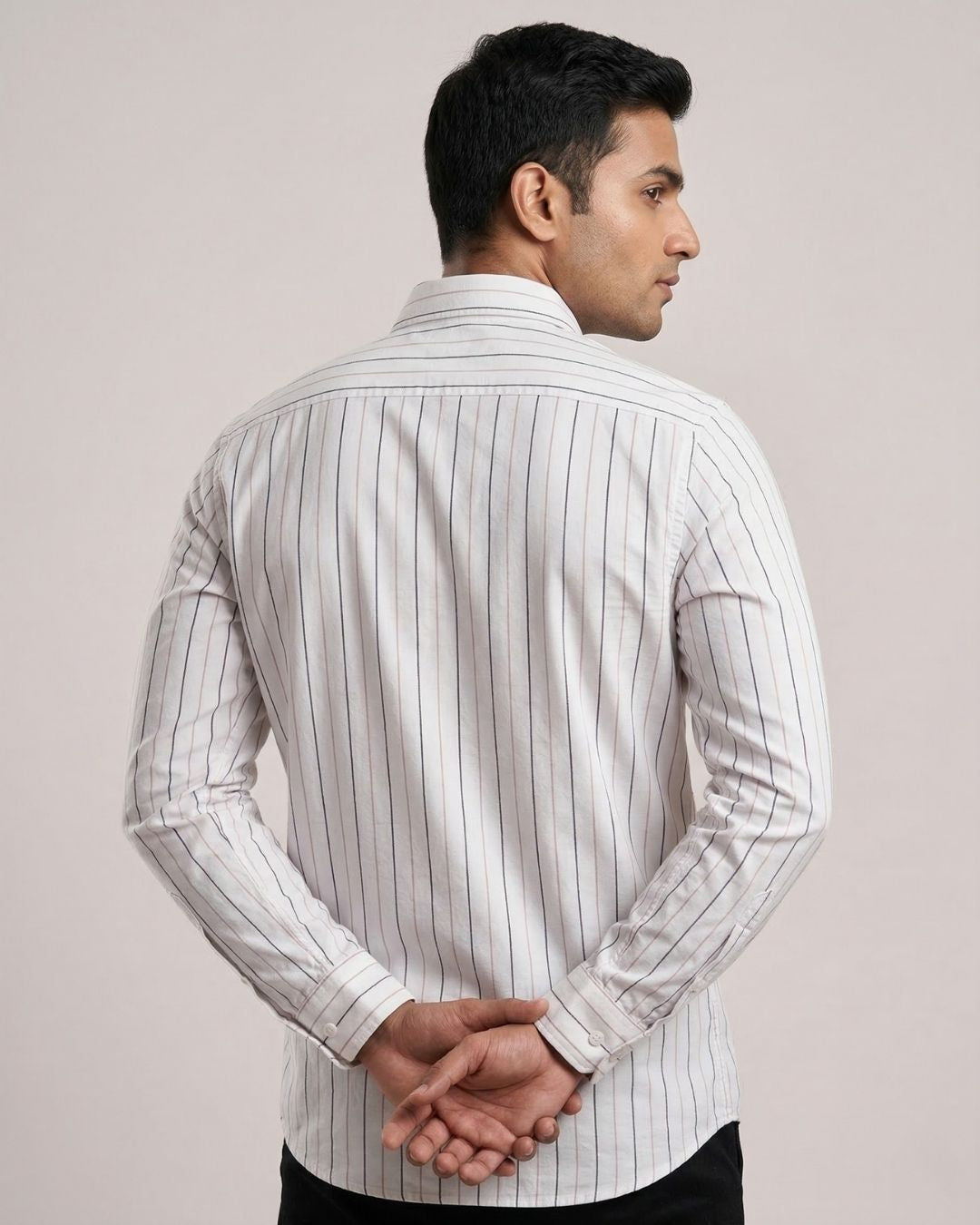 Man wearing a white shirt with thin black stripes against a plain background