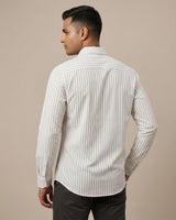 Man wearing a white shirt with black vertical stripes against a beige background
