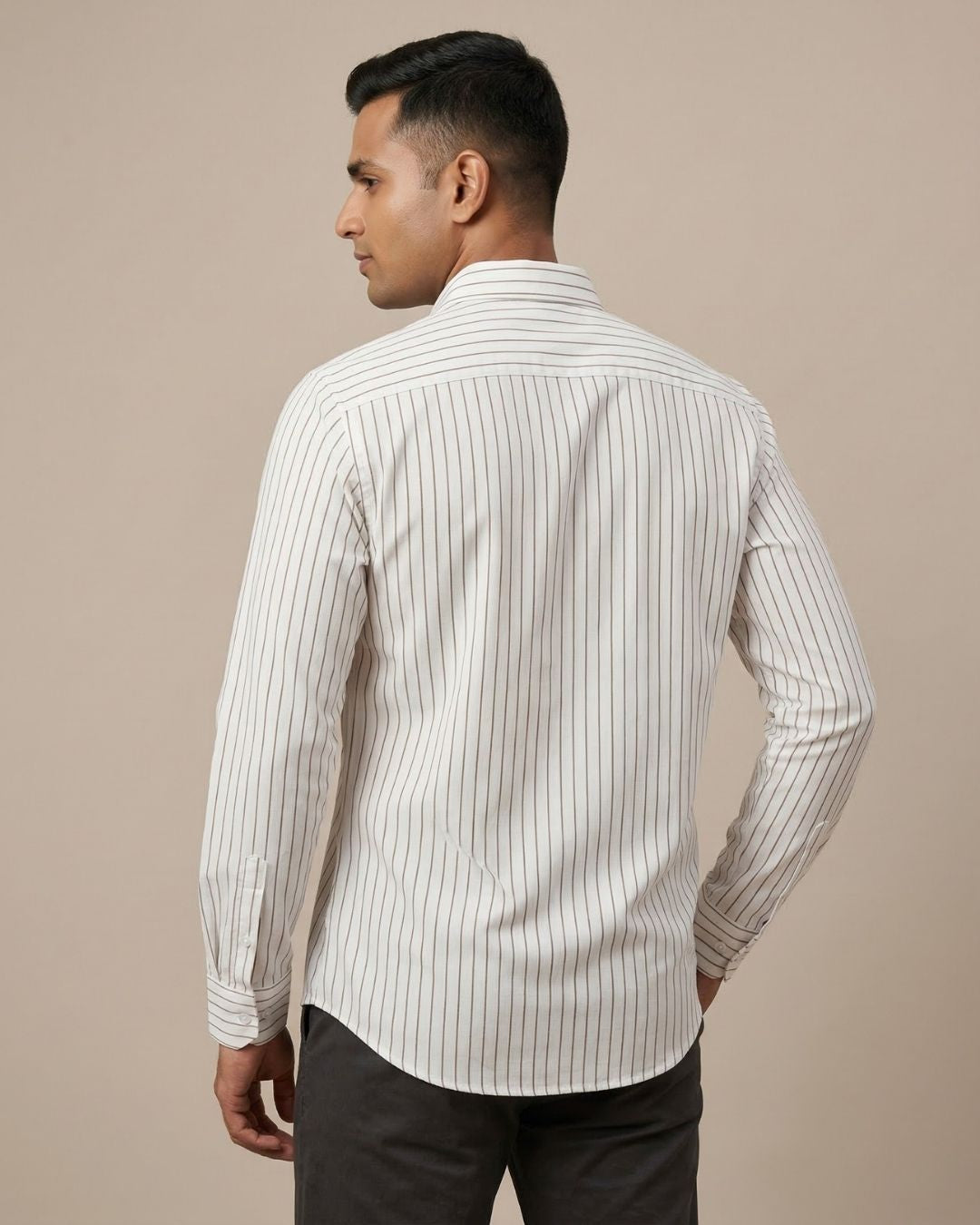 Man wearing a white shirt with black vertical stripes against a beige background