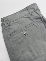 Close-up of gray trousers showing the waistband, belt loops, and a side pocket with a single visible button.