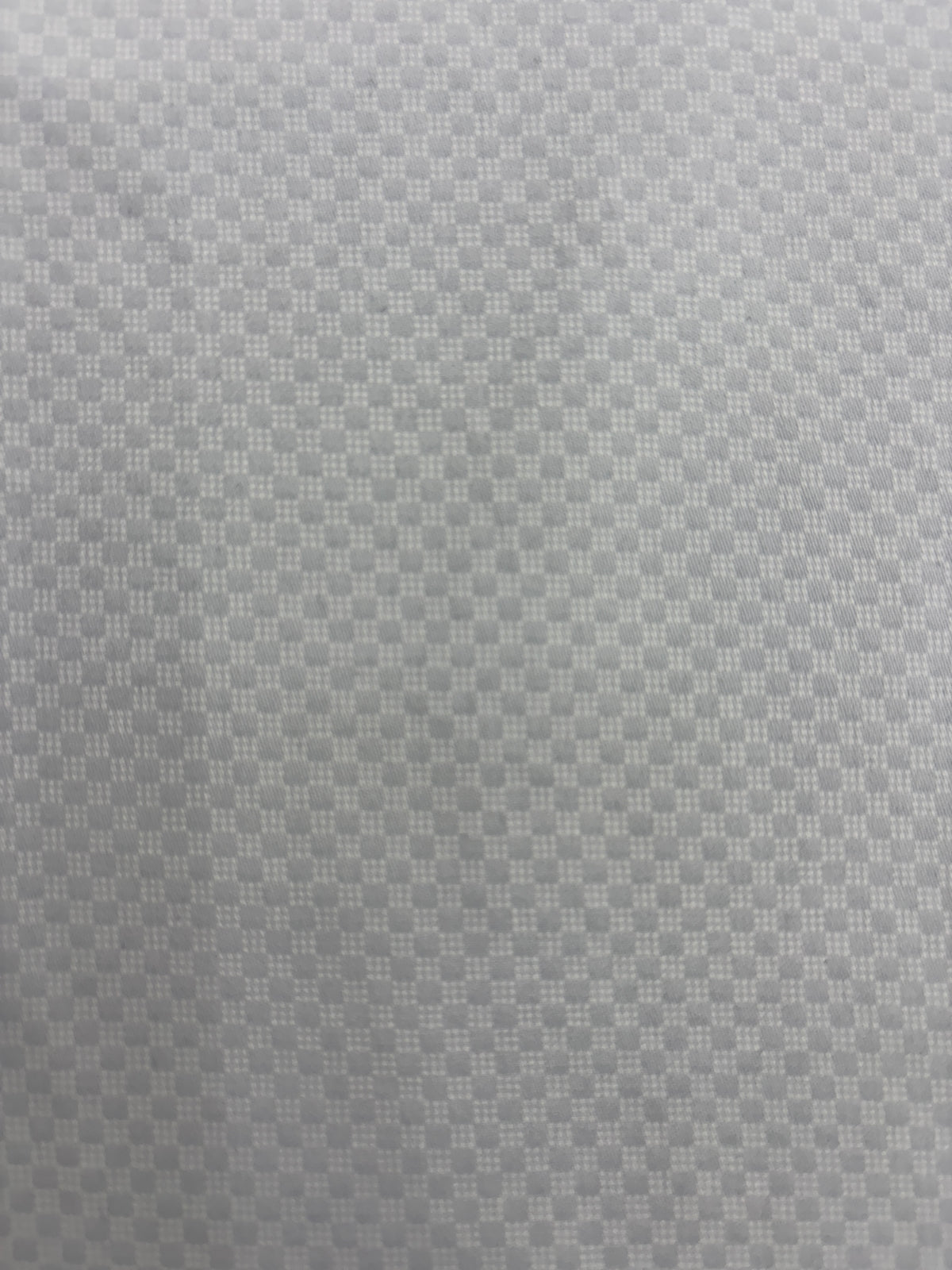 A close-up of a light gray textured fabric with a repeating geometric pattern.
