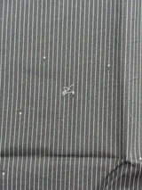 A close-up of a dark gray pinstriped fabric with thin white vertical stripes and a small white embroidered logo in the center.