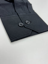 Close-up of a dark navy pinstriped shirt cuff with two dark buttons, laid flat on a white surface.