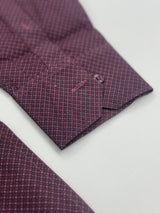 Close-up of a patterned dress shirt cuff in a deep purple and red micro-check design, laid flat on a white surface.