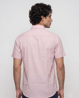 A man wearing a light pink short-sleeve button-down shirt, shown from the back against a plain light gray studio background.