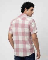 A man wearing a short-sleeve pink and white checkered shirt, shown from a three-quarter back view against a light gray studio background.
