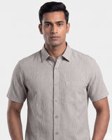 A man wearing a short-sleeve button-up shirt with fine vertical pinstripes in a light beige and gray colorway, photographed against a solid light gray background.