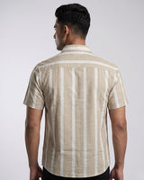 A man viewed from the back wearing a short-sleeve button-up shirt with vertical beige and white stripes, set against a plain light gray studio background.