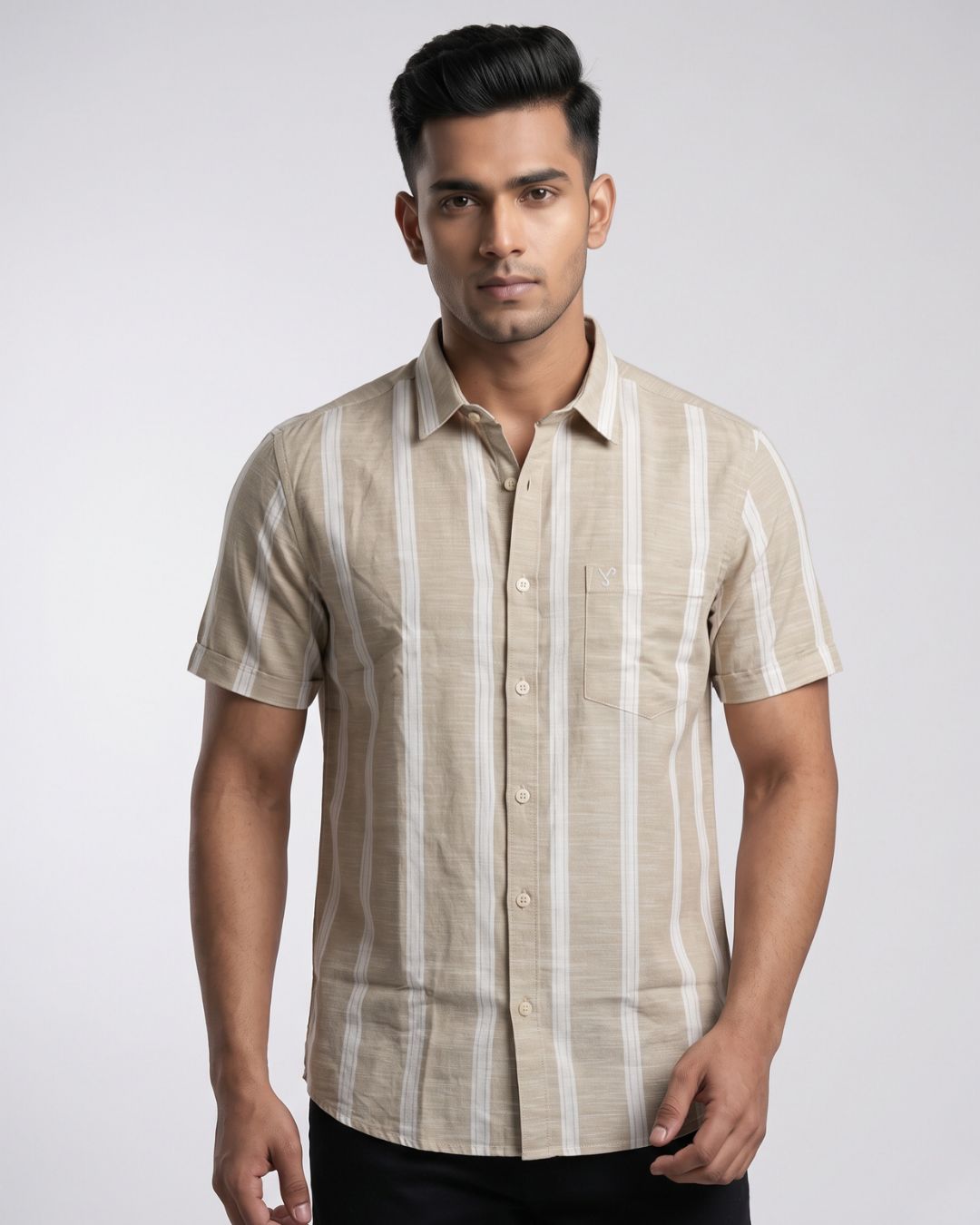 A man wearing a beige short-sleeve button-up shirt with vertical off-white stripes, photographed against a light gray studio background.