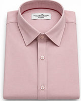 A folded light pink dress shirt with a classic collar and button-down front, featuring a visible 'Yellow Pepper Paris' brand label inside the collar.