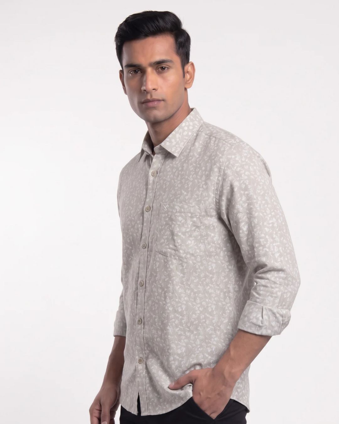 A man wearing a light beige long-sleeve button-down shirt with a small white floral pattern, posed against a plain white studio background.