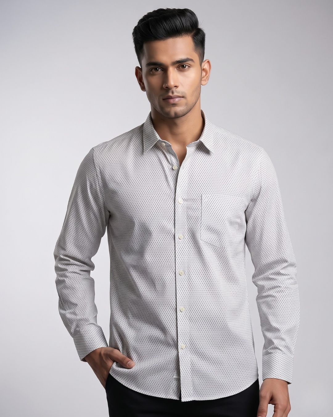 A man wearing a light gray and white micro-patterned long-sleeve button-down shirt, standing against a neutral gray studio background.