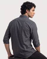 A man wearing a dark gray long-sleeve linen shirt, shown from a three-quarter back view while seated against a plain light background.