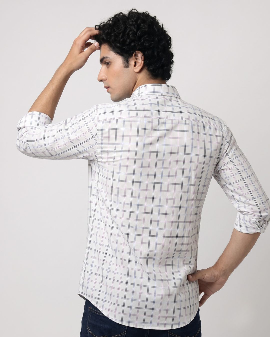 A man wearing a white long-sleeve plaid button-down shirt with blue and gray lines, shown from the back against a light gray studio background.