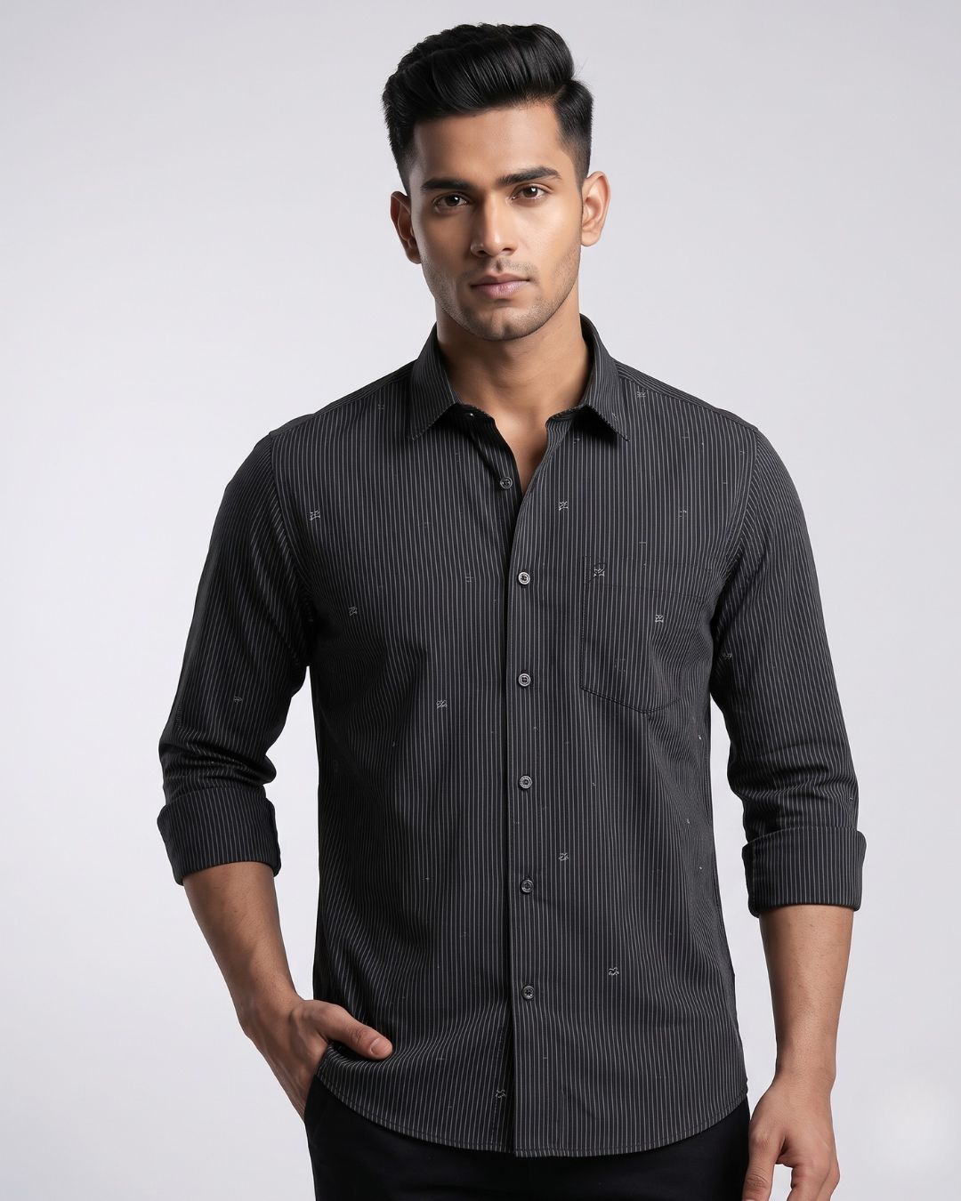 A man wearing a dark gray long-sleeve button-down shirt with a subtle vertical stripe pattern and small embroidered details, posed against a light gray studio background.