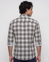 A man wearing a gray and white plaid button-down shirt, photographed from the chest up against a light gray studio background.