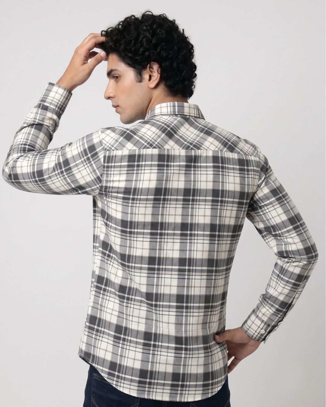 A man wearing a long-sleeve plaid button-up shirt, shown from the back. The shirt features a black, gray, and off-white plaid pattern.