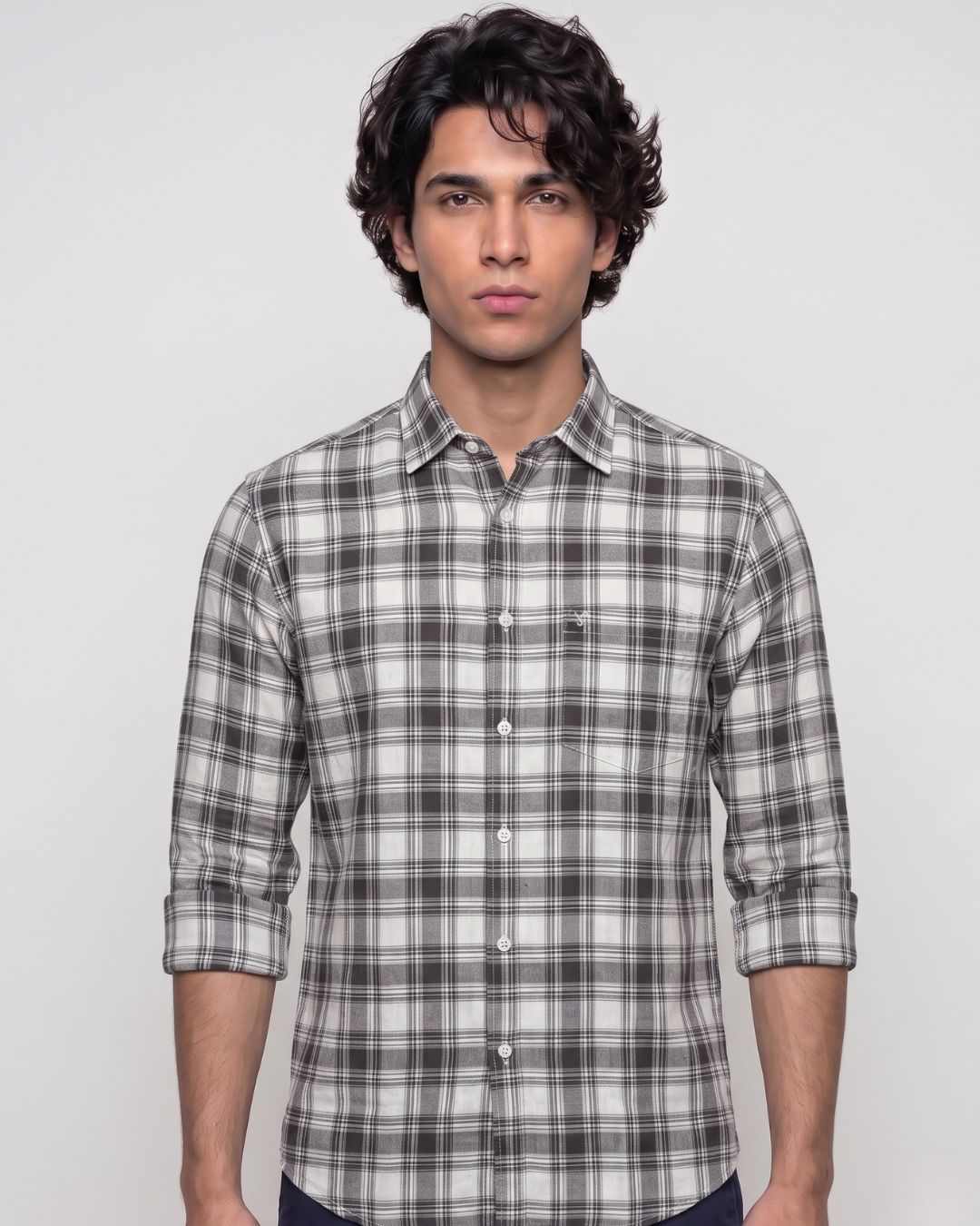 A man wearing a gray and white plaid button-down shirt, photographed from the chest up against a light gray studio background.