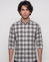 A man wearing a gray and white plaid button-down shirt, photographed from the chest up against a light gray studio background.