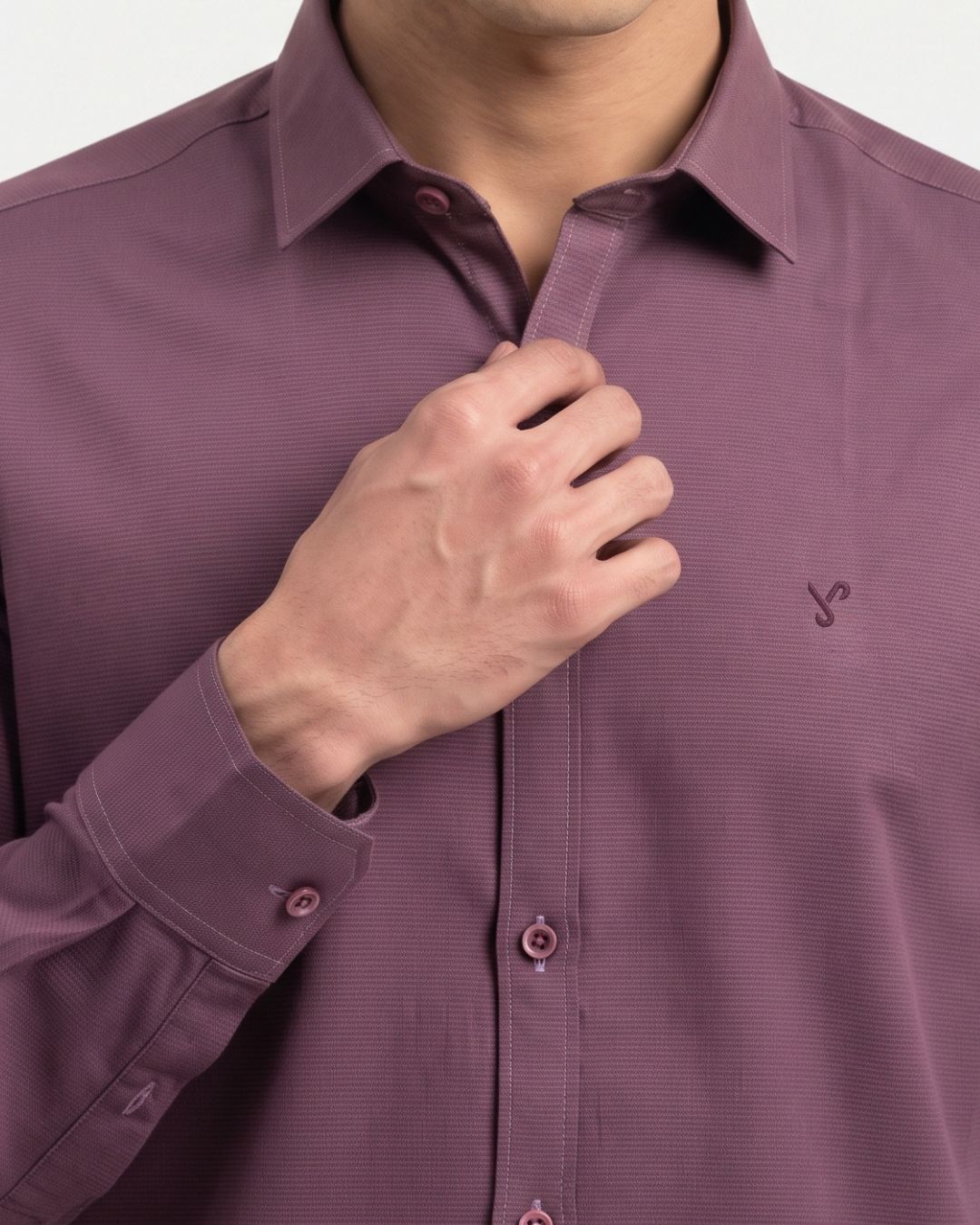 A close-up of a man wearing a textured, muted purple long-sleeve button-down shirt, adjusting the collar with his hand.