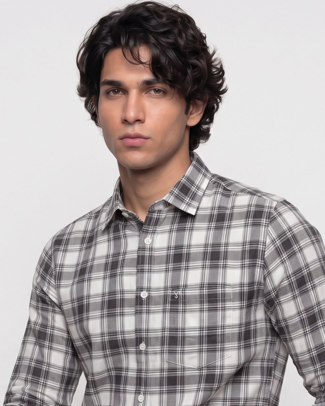 A man wearing a gray and white plaid button-down shirt, photographed from the chest up against a light gray studio background.