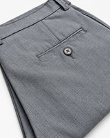 Close-up of folded gray plaid trousers showing the back pocket with a button closure and belt loop.