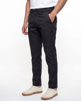 A person wearing slim black trousers with side pockets, paired with a white t-shirt and off-white sneakers, shown from the waist down against a plain white studio background.