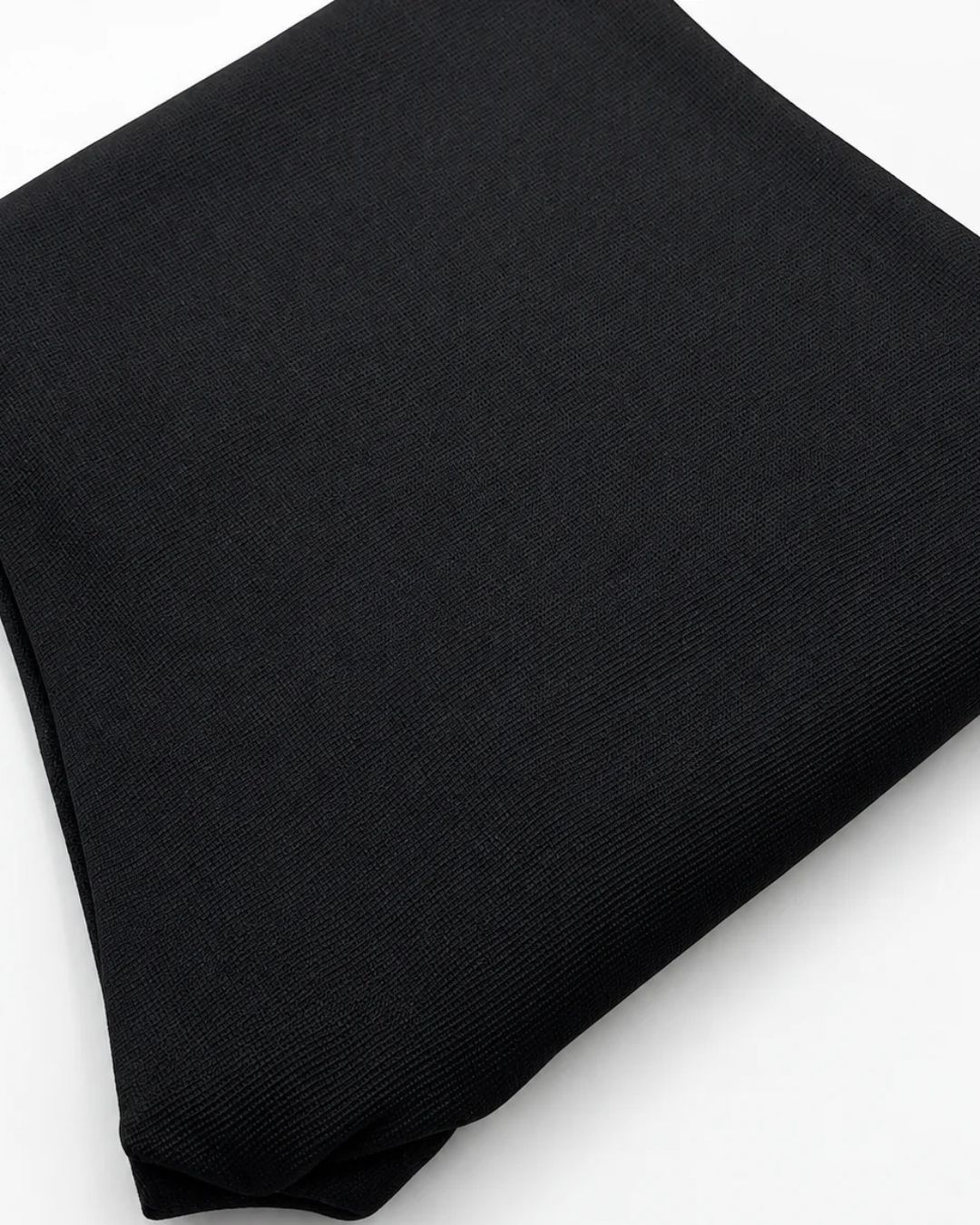 A folded black ribbed knit fabric garment, likely a sweater or knit top, shown on a plain white background.