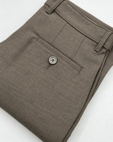 A close-up of folded brown trousers showing the waistband, belt loops, front pocket, and a single button closure on a white background.