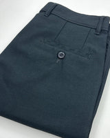 A close-up of folded dark charcoal gray trousers showing the waistband, belt loops, and a buttoned welt pocket.